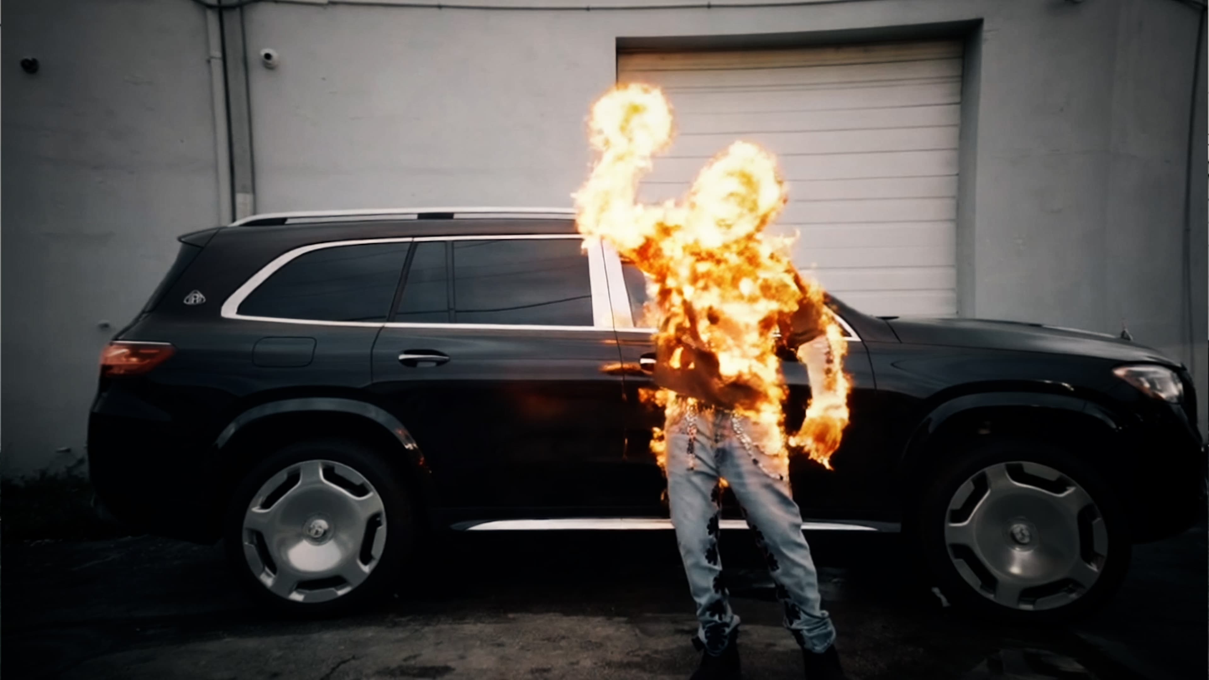 Burning figure next to a black Maybach on a Lossvisuals music video shoot